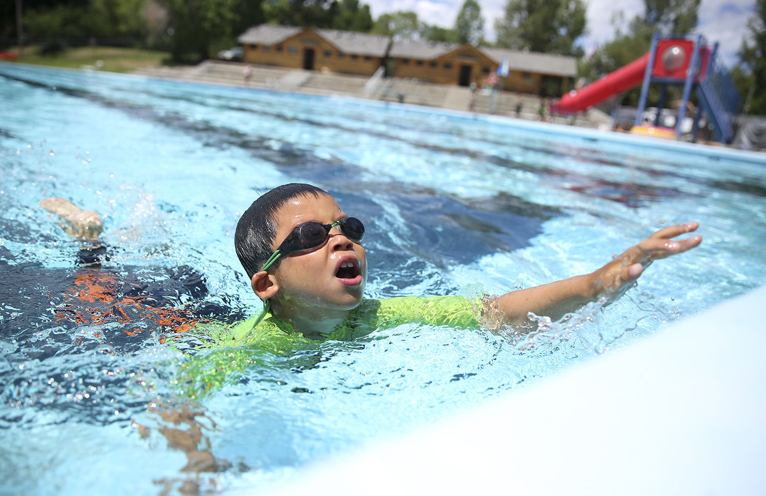 JinEu Chea, 7, stretches out to grab the wall after swimming the width of the pool
